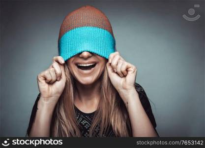 Portrait of a cheerful smiling woman wearing a hat on her face, playing and having fun, concept of enjoying life, youth funky fashion