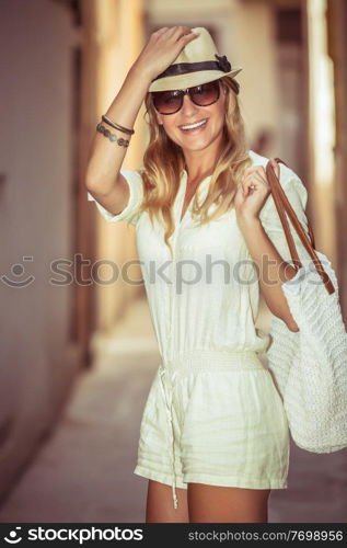 Portrait of a cheerful stylish woman enjoying shopping, pretty girl wearing fashionable sunglasses and hat, happy summer vacation