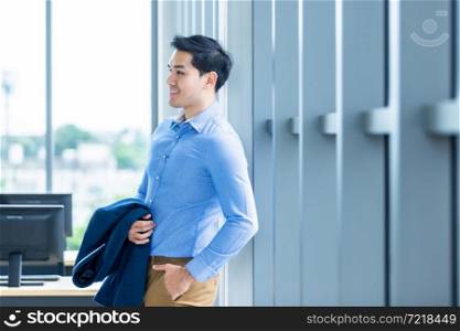 Portrait of a cheerful successful feeling winner handsome young asian businessman wear a business suit of man in blue jacket and blue shirt at window In the office room background.