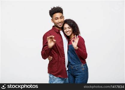 Portrait of a cheerful young african couple standing together and showing ok gesture isolated over white background.. Portrait of a cheerful young african couple standing together and showing ok gesture isolated over white background