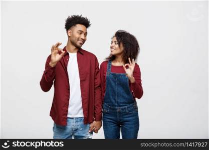Portrait of a cheerful young african couple standing together and showing ok gesture isolated over white background.. Portrait of a cheerful young african couple standing together and showing ok gesture isolated over white background