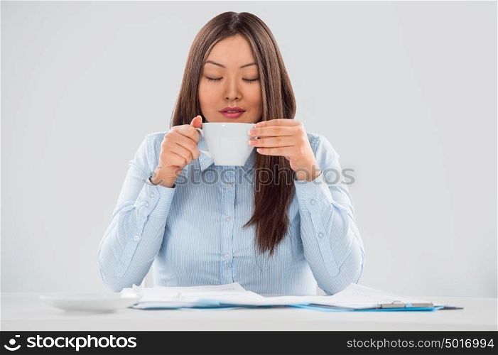 Portrait of a cheerful young business woman holding coffee cup with papers in front