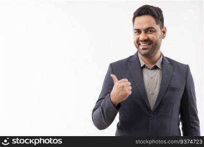 Portrait of a cheerful young businessman in formal outfit pointing sideways