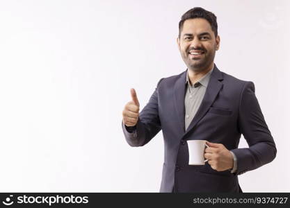 Portrait of a cheerful young businessman looking at camera and showing thumbs up