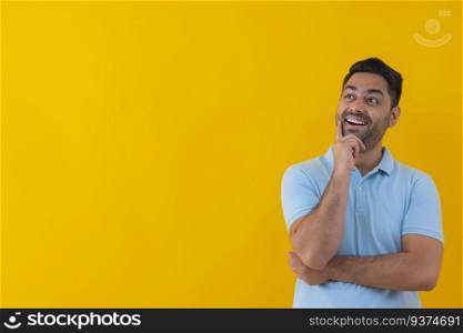 Portrait of a cheerful young man looking elsewhere with hand on cheek against yellow background
