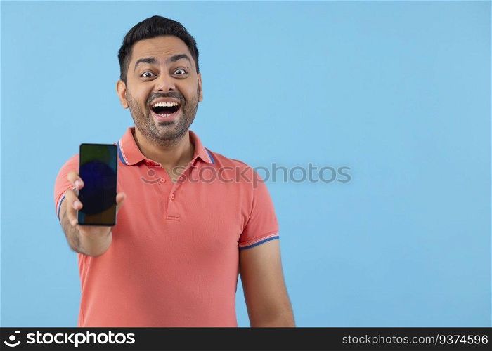 Portrait of a cheerful young man showing his Smartphone in front of camera
