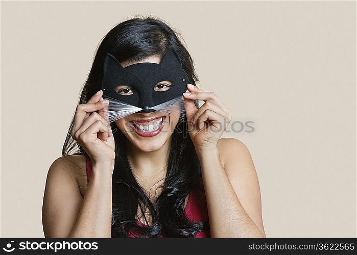 Portrait of a cheerful young woman wearing eye mask over colored background