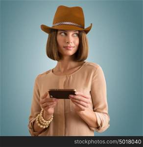 Portrait of a cheerful young woman wearing hat using her smartphone