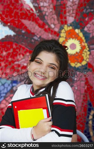 Portrait of a cheerleader holding books and smiling