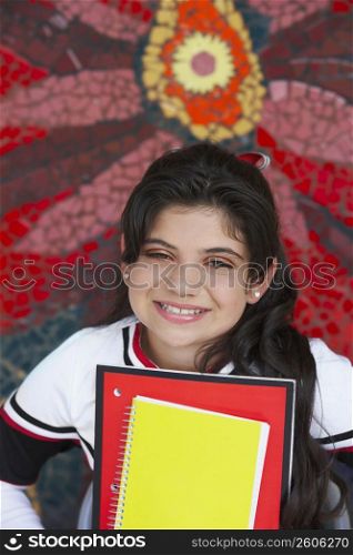 Portrait of a cheerleader holding books and smiling