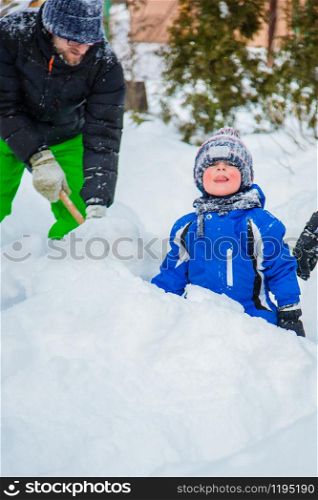 Portrait of a child and a warm winter suit with gloves, playing on a winter day outdoors. Blind snowman, play snowballs child fun.. Portrait of a child and a warm winter suit with gloves, playing on a winter day outdoors.