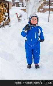 Portrait of a child and a warm winter suit with gloves, playing on a winter day outdoors. Blind snowman, play snowballs child fun.. Portrait of a child and a warm winter suit with gloves, playing on a winter day outdoors.