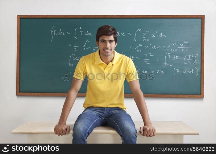 Portrait of a college student sitting on a table smiling