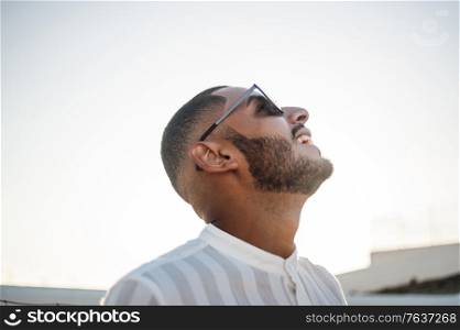 Portrait of a confident and casual man, modern muslim wearing sunglasses, natural outdoor light.