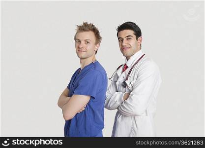 Portrait of a confident doctor and male nurse standing with arms crossed over gray background