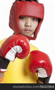 Portrait of a confident young boy wearing head protector and boxing gloves over white background