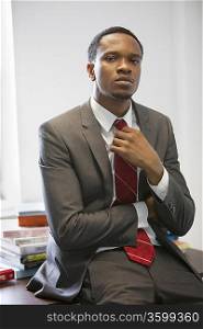 Portrait of a confident young businessman sitting on desk