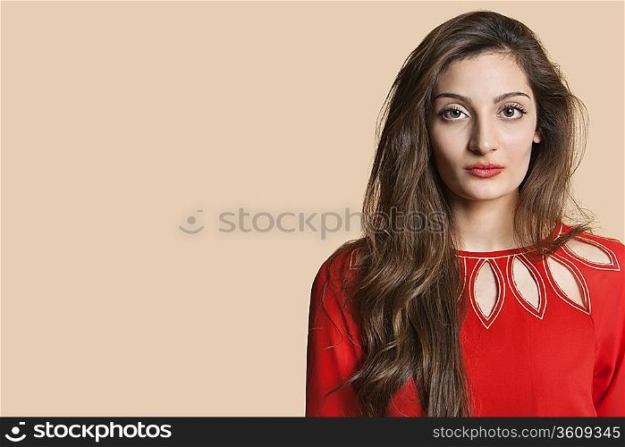 Portrait of a confident young woman in red over colored background