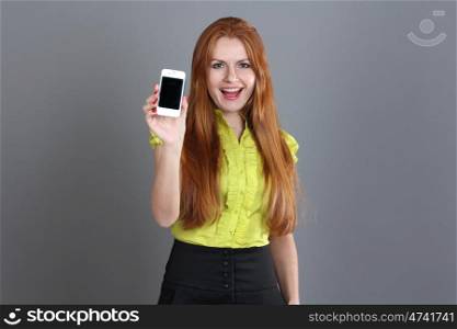Portrait of a confident young woman showing mobile phone against grey background