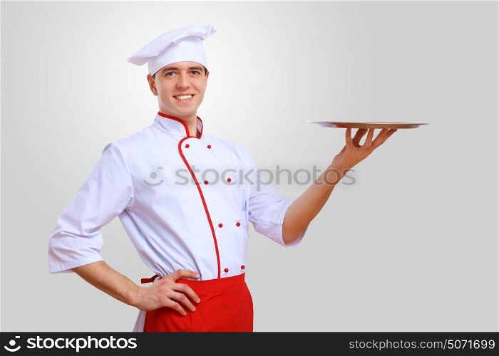 Portrait of a cook. Young male chef in red apron against grey background