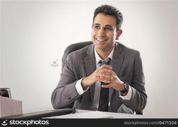 PORTRAIT OF A CORPORATE LEADER SITTING IN OFFICE AND HAPPILY THINKING