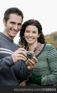 Portrait of a couple holding a digital camera and smiling