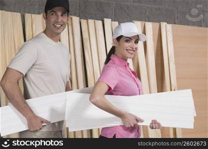 Portrait of a couple holding sheets of plywood