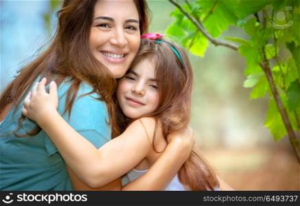 Portrait of a cute baby girl with pleasure and love hugging her dear mommy, mother with daughter spending time in spring park, happy family life. Happy family life