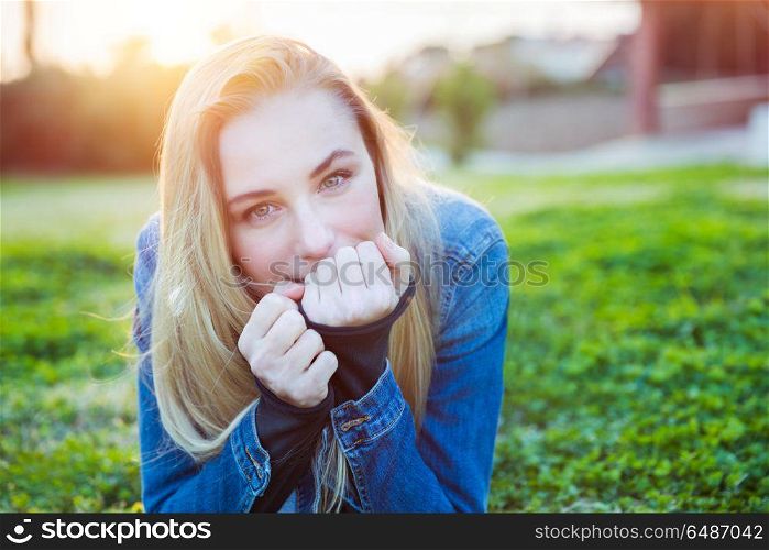Portrait of a cute blond female lying down on fresh green grass meadow on the backyard, enjoying warm sunny day, happy spring weekend in a countryside. Cute girl on spring meadow