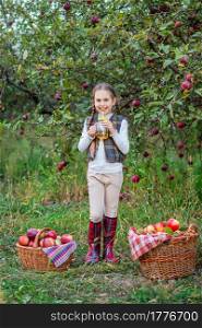 Portrait of a cute girl in a farm garden with a red apple. Autumn harvest of apples.. Portrait of a cute girl in a farm garden with a red apple.