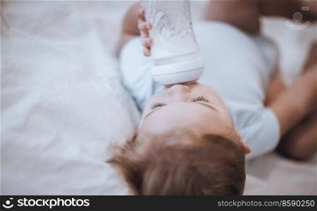 Portrait of a Cute Little Baby with Pleasure Drinking Formula Before Nap. Sleeping in Cute Child’s Bedroom. Happy Healthy Childhood.. Sweet Baby Drinking Formula