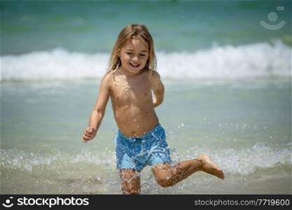 Portrait of a Cute Little Boy Running in the Water Making Splashes. Happy Child Enjoying Active Summer Holidays on the Beach Resort.. Happy Little Boy on the Beach