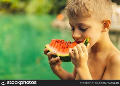 Portrait of a cute little boy with pleasure eating watermelon outdoors, enjoying fresh ripe juicy fruit, happy summer holidays