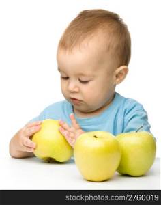 Portrait of a cute little child with three yellow apples, isolated over white