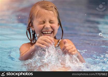 Portrait of a Cute Little Girl Having Fun and Splashing in the Pool. Spending Summer Weekend in Aquapark. Happy Summer Holidays. Carefree Childhood.. Happy Little Girl in the Pool