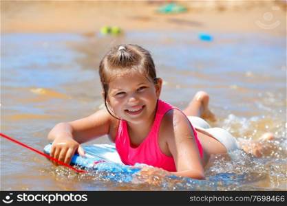Portrait of a Cute Little Girl Having Fun on the Beach. Pretty Child Swimming on the Body Board in the Nice Warm Sea Water. Happy Active Summer Holidays.