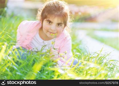 Portrait of a cute little girl having fun outdoors, adorable child playing on fresh green grass field in bright sunny day, happy and carefree childhood