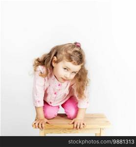 Portrait of a cute little girl sitting near a mirror with wooden calendar in the hands in the interior with Shabby chic decor 