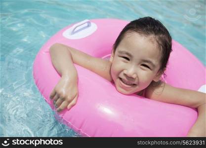 Portrait of a cute little girl swimming in the pool with a pink tube