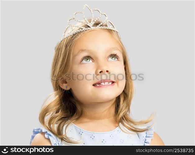 Portrait of a cute little girl wearing a princess crown and making a dreamy face