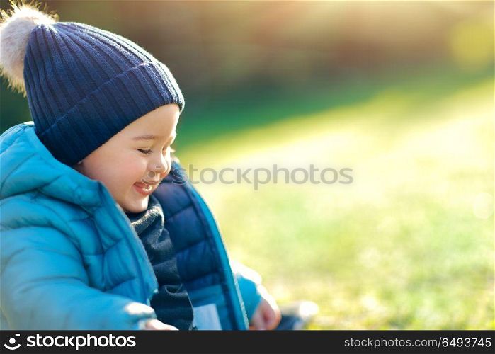 Portrait of a cute smiling baby boy with pleasure spending time outdoors, sweet toddler enjoying first warm and sunny spring days, happy carefree childhood. Happy boy outdoors