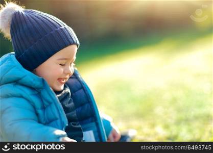 Portrait of a cute smiling baby boy with pleasure spending time outdoors, sweet toddler enjoying first warm and sunny spring days, happy carefree childhood. Happy boy outdoors
