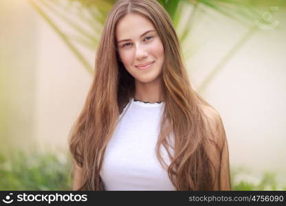 Portrait of a cute teenage girl outdoors over natural background, perfect appearance without makeup and with beautiful long natural hair, conceptual photo of beauty and freshness of youth. Beautiful youthful girl portrait