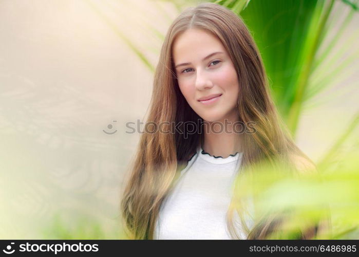 Portrait of a cute teenage girl outdoors over natural background, perfect appearance without makeup and with beautiful long natural hair, conceptual photo of beauty and freshness of youth. Beautiful youthful girl portrait
