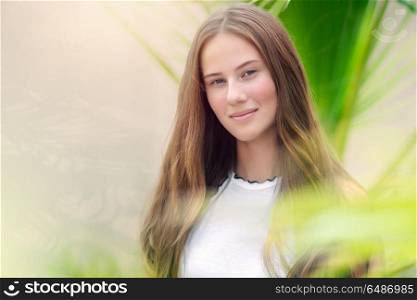 Portrait of a cute teenage girl outdoors over natural background, perfect appearance without makeup and with beautiful long natural hair, conceptual photo of beauty and freshness of youth. Beautiful youthful girl portrait
