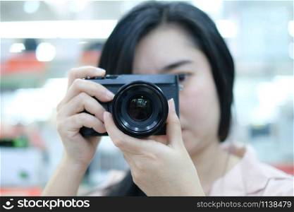 Portrait of a cute woman a picture with a digital camera at the blurred background, Photography concept