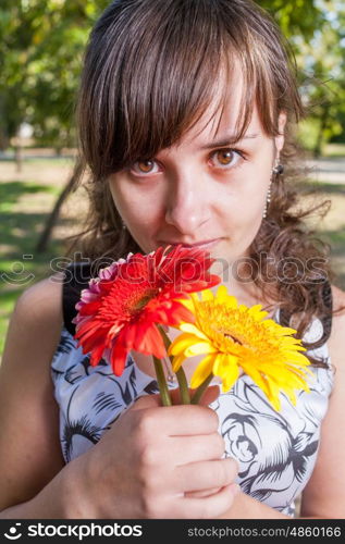 Portrait of a cute women with three flowers looking at camera.