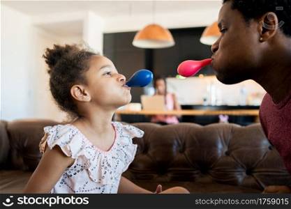 Portrait of a daughter and father having fun together and playing with balloons while staying at home. Monoparental concept.