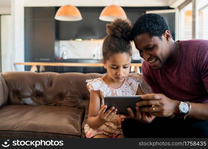 Portrait of a daughter and father using a digital tablet while staying at home. Monoparental concept.