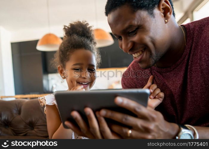 Portrait of a daughter and father using a digital tablet while staying at home. Monoparental concept.